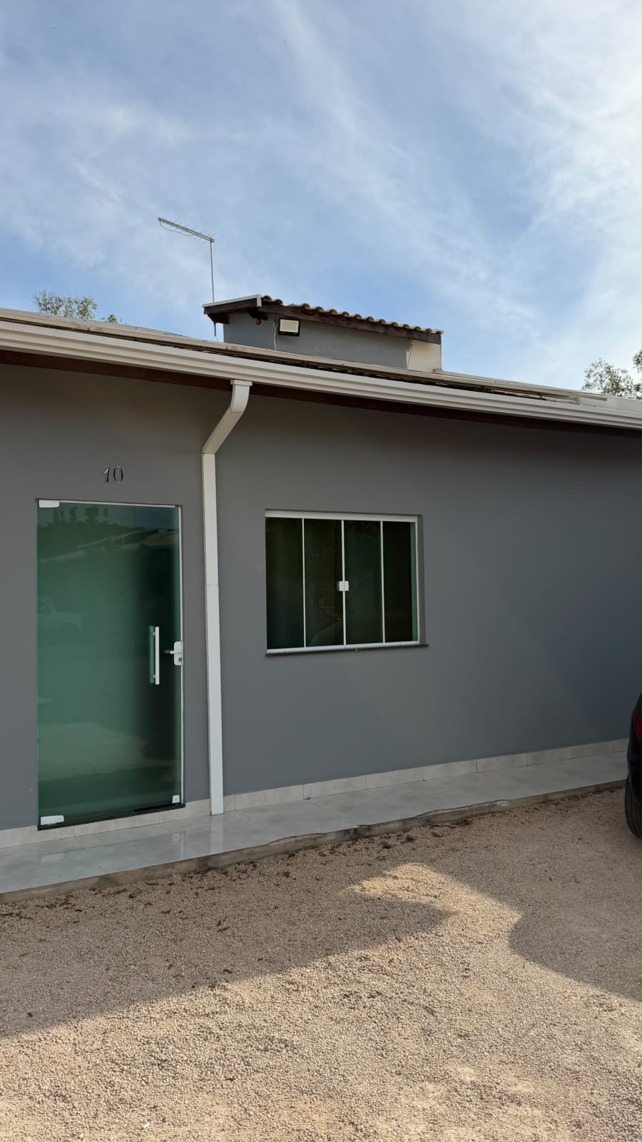 Fachada da unidade da Bella Home com porta de vidro e estacionamento